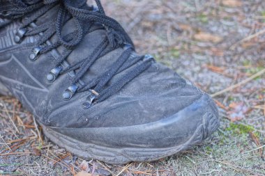 Deri ve kumaştan yapılmış siyah bir ayakkabının parçası Gri bir zeminde duruyor