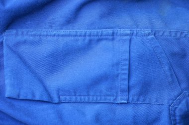 Giysilerinde cebi olan pantolonun mavi kumaşı.