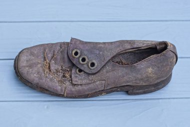 Eski, kahverengi, yırtık bir deri bot gri tahta bir masanın üzerinde yatıyor.