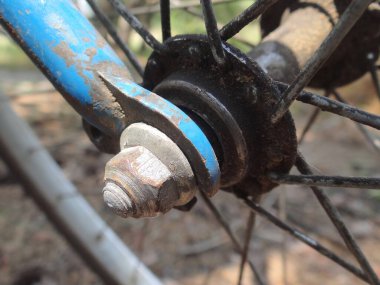 Bir yaz caddesinde mavi bir bisikletin ön tekerleğinde siyah telleri olan gri metal bir merkez.