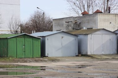 Şehir caddesinde asfalt üzerinde üç kapalı gri yeşil demir garaj.