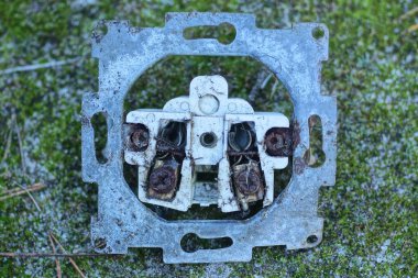 one old rusty white black electrical outlet lies on the ground and green moss on a summer street clipart