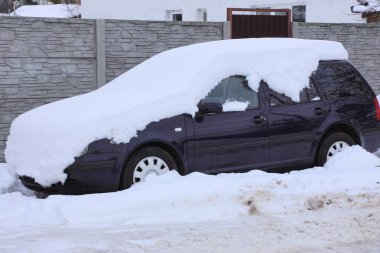 Kış caddesinde kar yığınının altında mavi bir yolcu vagonunun parçası.