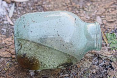 Donmuş suyla dolu büyük, eski, kirli bir kavanoz kış sokağında yerde yatıyor.