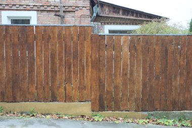 Kırsal kesimdeki yeşil çimlerde bulunan ahşap tahtalardan yapılmış uzun kahverengi bir duvarın parçası.