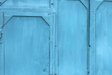Eski demir bir duvar ve kapının mavi metal dokusu. Sokakta dikişler var.