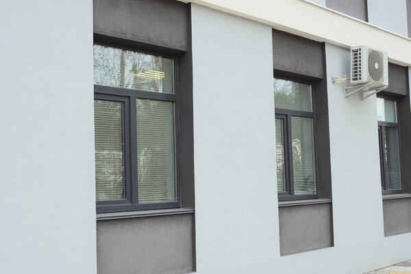 ряд из трех черных окон на бетонной коричневой стене большого здания на улице