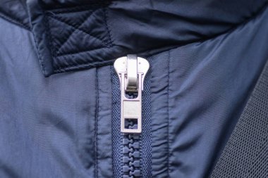 Mavi sentetik kumaşta beyaz, kapalı, metalik bir fermuar.