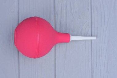 Büyük kırmızı plastik bir ampul gri tahta bir masada yatıyor.