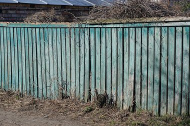 Kırsal sokaktaki tahtalardan eski, uzun, yeşil, ahşap duvar çitleri.