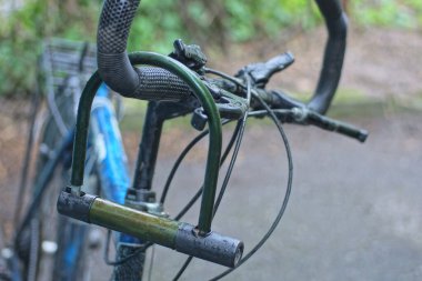 Kapalı bisiklet kilidi şehir caddesinde siyah bisiklet gidonunda asılı.