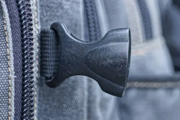 bir siyah kapalı plastik karabinalı gri sırt çantasına yapışmış.