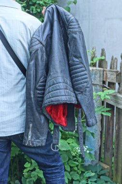 Bir adam Spring Caddesi 'nde elinde siyah deri ceket tutuyor.