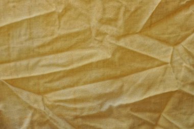 Buruşmuş eski bir kumaş parçasının sarı kumaşı.