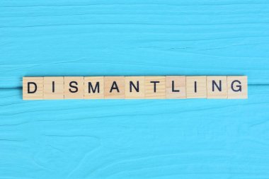 Tahta gri harflerden yapılmış kelimenin sökülmesi mavi bir arka planda yatıyor.