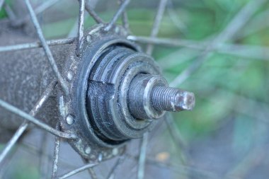 Bir yaz caddesinde bisikletin ön tekerleğinde telleri olan gri metal bir merkez.