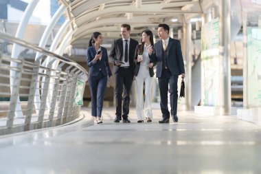 İş adamları modern ofis, liderlik konsepti ve iş başarısı önünde yürür ve birbirleriyle konuşurlar.