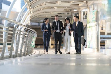 İş adamları modern ofis, liderlik konsepti ve iş başarısı önünde yürür ve birbirleriyle konuşurlar.