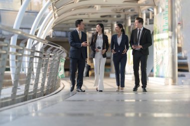 İş adamları modern ofis, liderlik konsepti ve iş başarısı önünde yürür ve birbirleriyle konuşurlar.