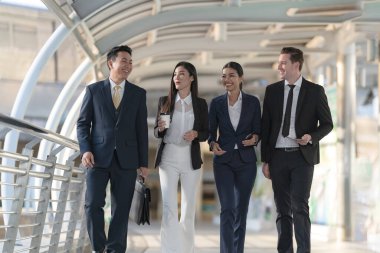 İş adamları modern ofis, liderlik konsepti ve iş başarısı önünde yürür ve birbirleriyle konuşurlar.