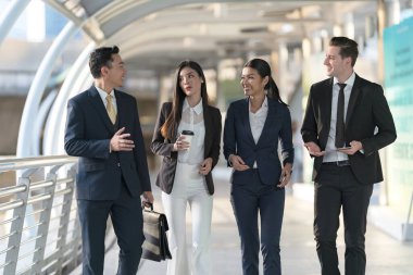 İş adamları modern ofis, liderlik konsepti ve iş başarısı önünde yürür ve birbirleriyle konuşurlar.