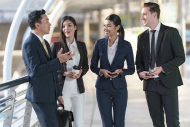 İş adamları modern ofis, liderlik konsepti ve iş başarısı önünde yürür ve birbirleriyle konuşurlar.