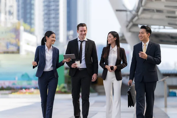 İş adamları modern ofis, liderlik konsepti ve iş başarısı önünde yürür ve birbirleriyle konuşurlar.