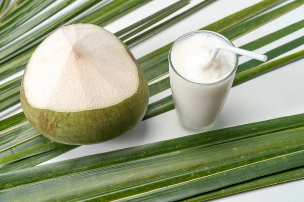 A glass of sweet coconut water coconut fragrance with coconut leaves background.