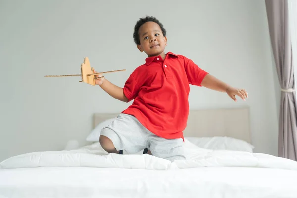 小さな男の子は 彼の部屋の床におもちゃの飛行機で遊んでいるパイロットであることを想像しています — ストック写真