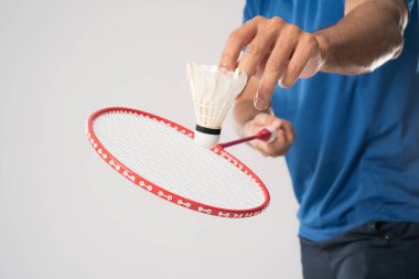 Spor giyim sektöründe bir badminton oyuncusu elinde raket ve beyaz arka planda mekik taşır.