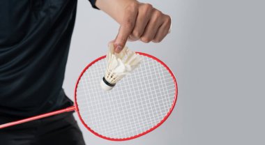 Spor giyim sektöründe bir badminton oyuncusu elinde raket ve beyaz arka planda mekik taşır.