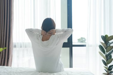 Güzel kız sabah uyanıyor. Güneş büyük pencereden parlıyor. Yeni günü sıcak günışığıyla selamlayın..