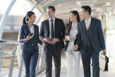 İş adamları modern ofis, liderlik konsepti ve iş başarısı önünde yürür ve birbirleriyle konuşurlar.