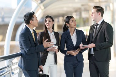 İş adamları modern ofis, liderlik konsepti ve iş başarısı önünde yürür ve birbirleriyle konuşurlar.