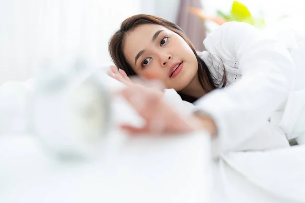 stock image Alarm clock with good day against background happy young woman relaxing in bed after waking up in the morning sunshine.