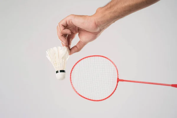 A badminton player in sportswear stands holding a racket and shuttlecock in the white background