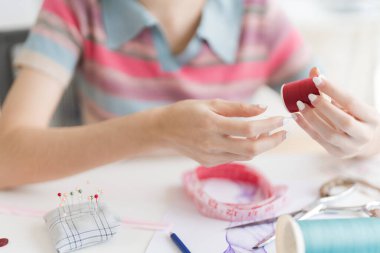 Elbise kesme ve tasarlama araçları ile çalışan genç ve güzel tasarımcının kırpılmış resmi.