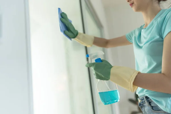 青のラグとスプレー洗剤ハウスクリーニングと緑の手袋のクリーニングドアの女性の手 — ストック写真