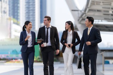 İş adamları modern ofis, liderlik konsepti ve iş başarısı önünde yürür ve birbirleriyle konuşurlar.