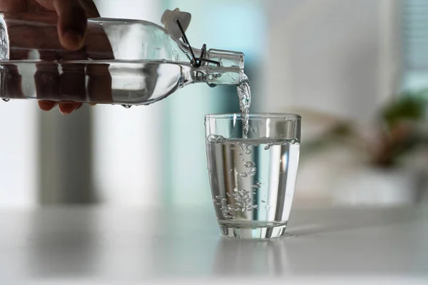 Pour the water from the water bottle into the glass at home.