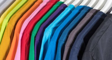 Colorful t-shirts hanging on a rack, background