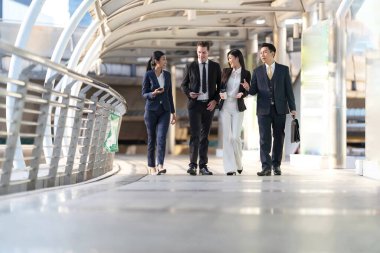 İş adamları modern ofis, liderlik konsepti ve iş başarısı önünde yürür ve birbirleriyle konuşurlar.