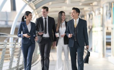 İş adamları modern ofis, liderlik konsepti ve iş başarısı önünde yürür ve birbirleriyle konuşurlar.