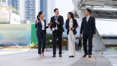 İş adamları modern ofis, liderlik konsepti ve iş başarısı önünde yürür ve birbirleriyle konuşurlar.