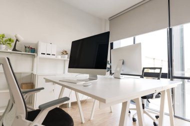 White table and chair with computer monitor and modern file cabinet in white home office interior