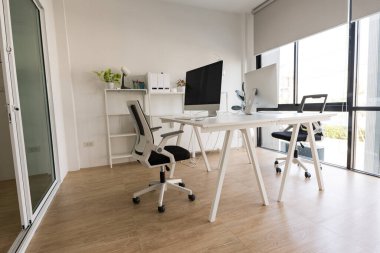 White table and chair with computer monitor and modern file cabinet in white home office interior