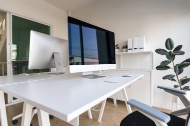 White table and chair with computer monitor and modern file cabinet in white home office interior
