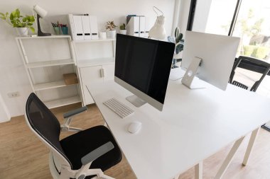White table and chair with computer monitor and modern file cabinet in white home office interior