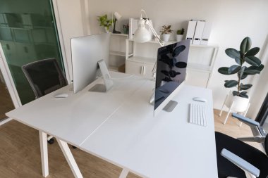 White table and chair with computer monitor and modern file cabinet in white home office interior