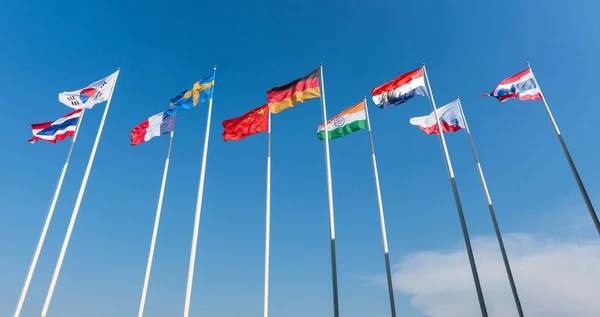 stock image The national flags of nine nations, Thailand, South Korea, France, Sweden, China, Germany, Czech Republic, Netherlands, India, flutter against a blue sky.